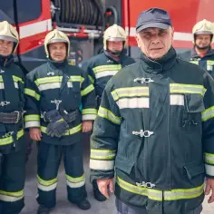 Strażacy w mundurach przy wozie strażackim. Zastanawiasz się, ile zarabia strażak?
