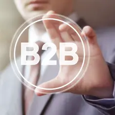 Biznes do biznesu, czyli b2b, to klucz do sukcesu wielu firm. Dłoń biznesmena dotyka ekranu z napisem B2B.