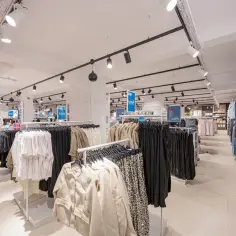 W sklepie LPP SA panuje porządek, ubrania wiszą na wieszakach, a ceny są widoczne.