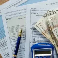 Polskie formularze podatkowe PIT, długopis, kalkulator i banknoty 200 zł. Czas rozliczyć się z fiskusem.