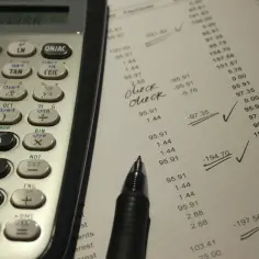 Kalkulator i arkusz z danymi finansowymi, gdzie widać ręczne zaznaczenia i obliczenia, sugerujące kontrolę **salda**.