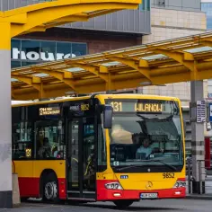 Żółto-czerwony autobus miejski na przystanku. Kierowca autobusu, jak i pasażerowie, czekają na dalszą podróż. Zastanawiasz się, ile zarabia kierowca autobusu?