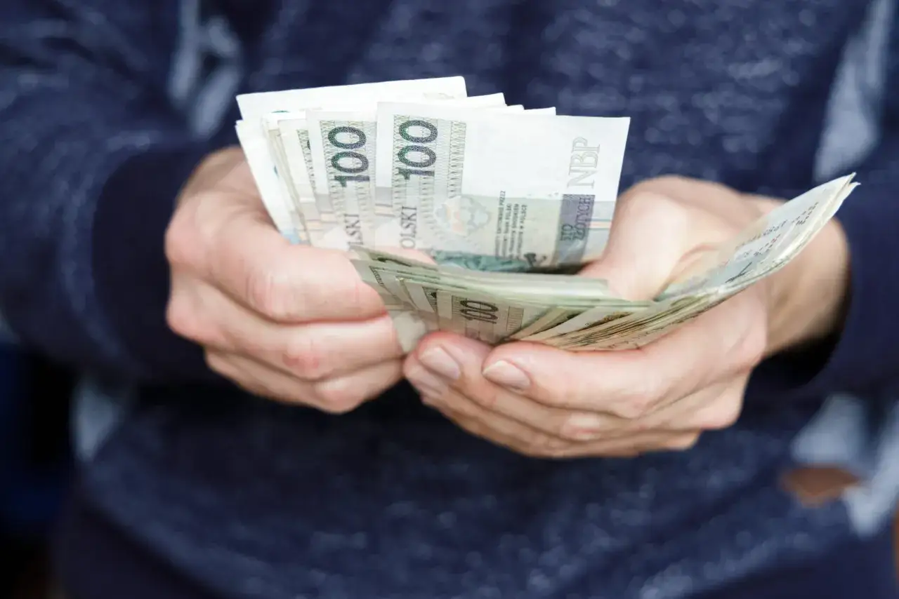 Dłonie trzymające plik banknotów 100 zł. Pilna pożyczka na dzisiaj może rozwiązać nagłe problemy finansowe.