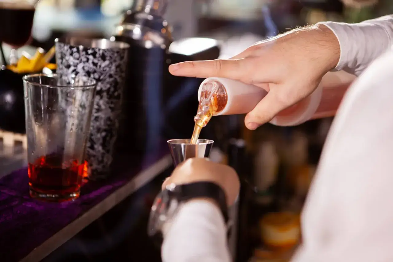 Barman nalewa alkohol do kieliszka.